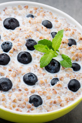 Buckwheat porridge in a bowl with mint leaves and blueberries.