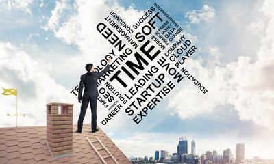 Young businessman standing on house roof and writing leadership 
