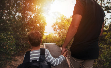 Father and son walking through trees outdoors
