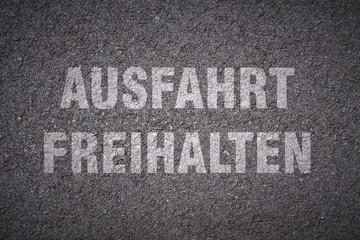 Fototapeta premium keep clear - german words lettering on asphalt texture background