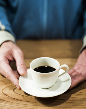 Close -up of man's hand holding coffee cup on table