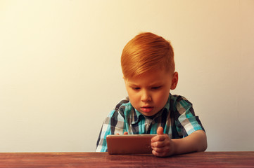 Naklejka premium Pensive child looking at the smartphone screen