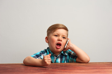 Naklejka premium Angry little boy sitting and talking on the phone