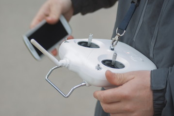 Obraz na płótnie Canvas Man operating flying drone with remote controller and smart phone