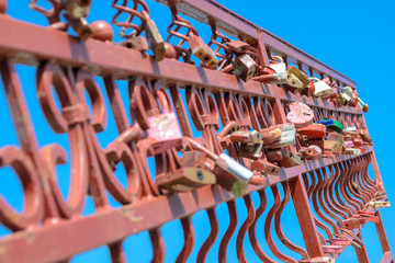 Love padlocks all over the metal fence on blue sky background
