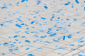 Blue paper party confetti on paving tiles. Decorations after party on asphalt. Background