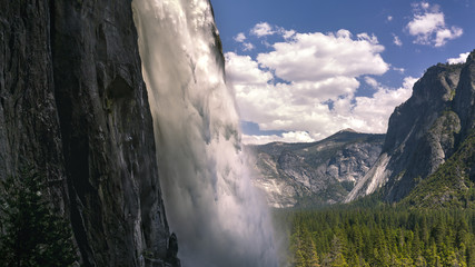 Close up of Yosemite Falls with a glowing stream and background of the valley