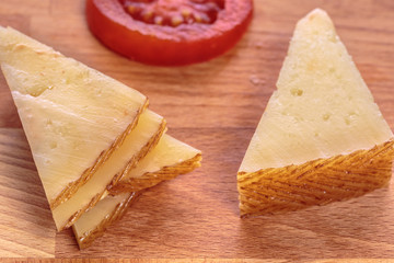 Manchego cheese slices over a wooden table