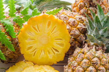 Fresh pineapple with slices on the wood texture background