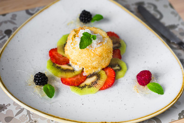 Close-up of a trendy dessert, fried ice cream with kiwi and strawberries, raspberries and blackberries, decorated with mint, sweet delicious, beautiful serve, restaurant