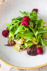 Close-up Warm salad, Duck liver with raspberry sauce, Arugula, raspberries, plate, tasty, fashionable food, restaurant, beautiful new dish serving, top view