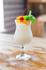 Close-up of sweet, delicious, non-alcoholic milkshake, decorated with orange slices, cherry and mint, dessert, restaurant