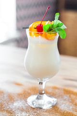 Close-up of sweet, delicious, non-alcoholic milkshake, decorated with orange slices, cherry and mint, dessert, restaurant