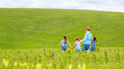 Fototapeta premium Happy family mother and children daughter girls laughing and running on meadow in summer