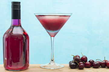 Cherry liqueur in a bottle, in a glass and fresh fruit