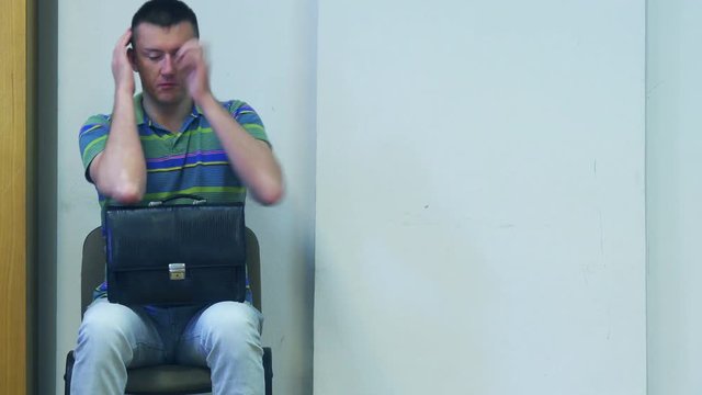 Sleepy businessman struggles with a dream, waiting in the waiting room