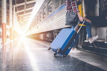 Alone traveler wait suitcases waiting for her train on platform of railway train station in summer. Alone travel concept.