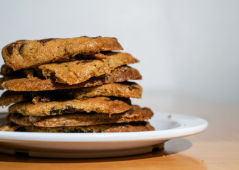 Stack of chocolate Chip Cookies in white plate on wooden table