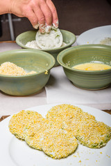 Applying cornmeal dredge to tomato slices