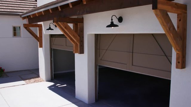 Two Garage Doors Close Lowering View from Corner of Garage. lowering from the exterior of a garage moving down as doors close to the floor
