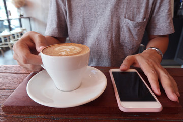 Man using smart phone and drinking coffee.