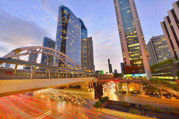 View of a pedestrian overpass in downtown of Bangkok City with high rise buildings in the background in evening light.