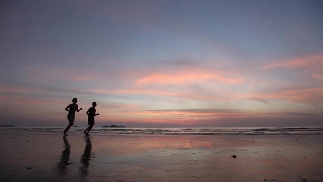 workout sport, two people runners  jogging at sunset on the beach