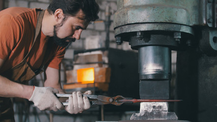 Molten metal is processed under pressure in the hands of a blacksmith