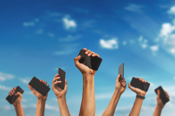 group of people's hands holding phones and rising them up against sky