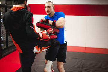Two professionals fighters training together with punching pads at gym