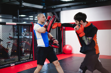 Two professionals fighters training together with punching pads at gym