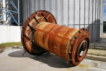 Rusting large machine part placed outdoors in a factory area