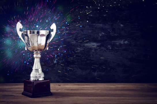 low key image of trophy over wooden table and dark background