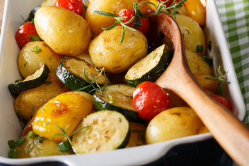 Tasty Food: potatoes baked with zucchini, bell pepper and tomatoes macro in a baking dish. horizontal
