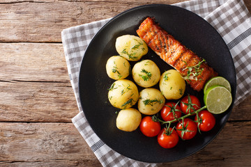 grilled salmon and boiled new potatoes close-up on a plate. horizontal top view