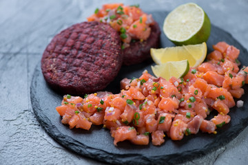 Close-up of salmon tartare served with beetroot cutlets, selective focus, studio shot
