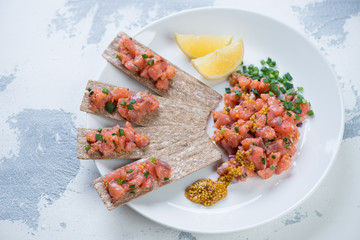 Glass plate with salmon tartar on a white concrete background, horizontal shot
