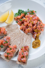 Close-up of salmon tartar served on a white glass plate, vertical shot, elevated view