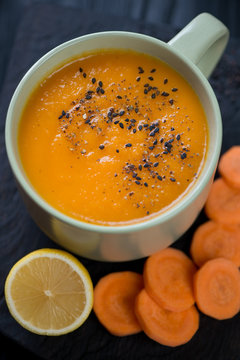 Close-up of carrot cream-soup served in a olive-colored cup, selective focus, shallow depth of field