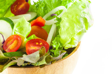 close up view of vegetables salad in a wooden bowl isolated on white