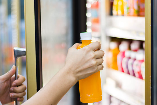 woman's hand open convenience store refrigerator shelves and pick product