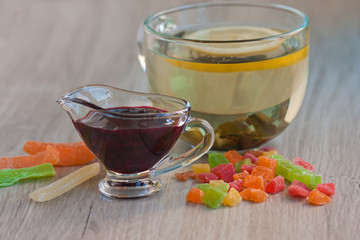 A large cup of fruit tea, a big yellow lemon, ripe fresh lime, a little candied fruit. Tea ceremony. Dessert. Fresh and dried fruits
