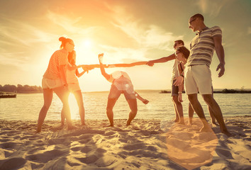 Friends funny game on the beach under sunset sunlight.