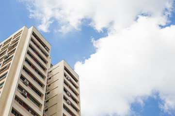 A tall modern residential tower block against a clear blue sky.