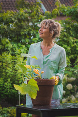 Attractive woman processes vegetable  in her garden looking up.