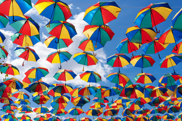Fototapeta na wymiar Colorful umbrellas background. Coloruful umbrellas urban street decoration. Hanging Multicoloured umbrellas over blue sky