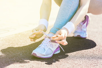 sport, fitness, people and lifestyle concept - close up of woman tying shoelaces outdoors