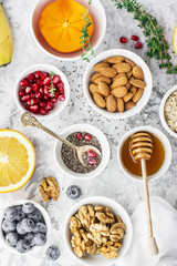 Ingredients for a healthy breakfast, nuts, oatmeal, honey, berries, fruits, blueberry, orange, pomegranate seeds, almonds, walnuts The concept of natural organic food in season Top view