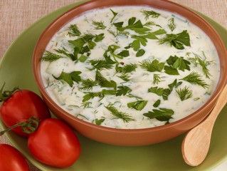 Bulgarian cold soup tarator with tomatoes and wood spoon