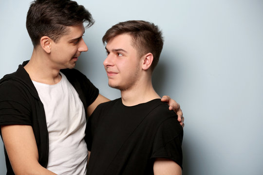 Happy gay couple posing on light background